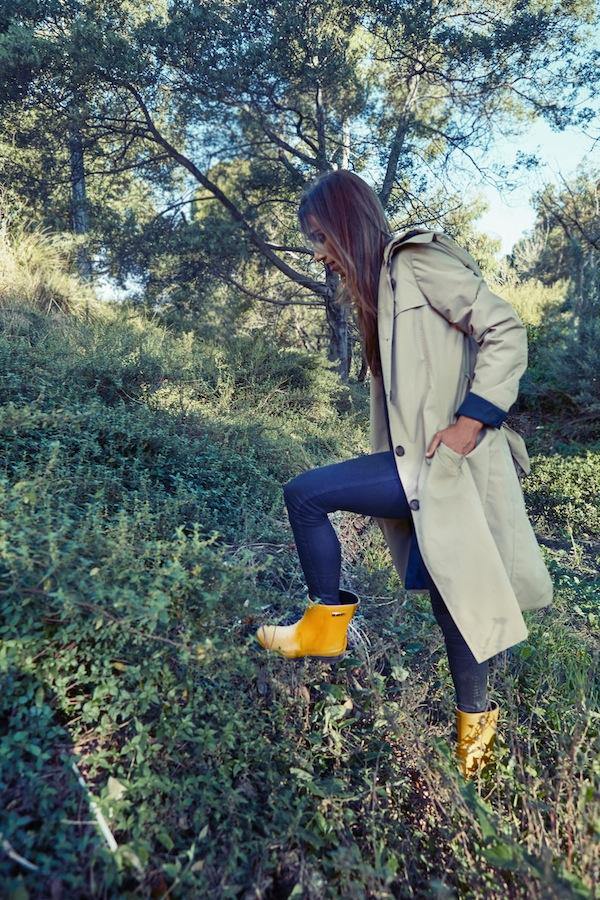 fashion journal magazine, woman walking up a hill wearing merry people raincoat and boots