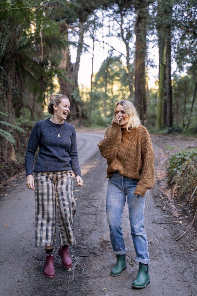 two women walking through a forest wearing merry people boots